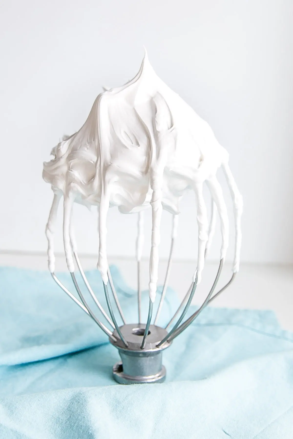This old-fashioned 7 minute frosting recipe is light, delicious, and easy to make. A pure white frosting that's perfect for a variety of delicious desserts. | livforcake.com Meringue frosting on a stand mixer whisk.