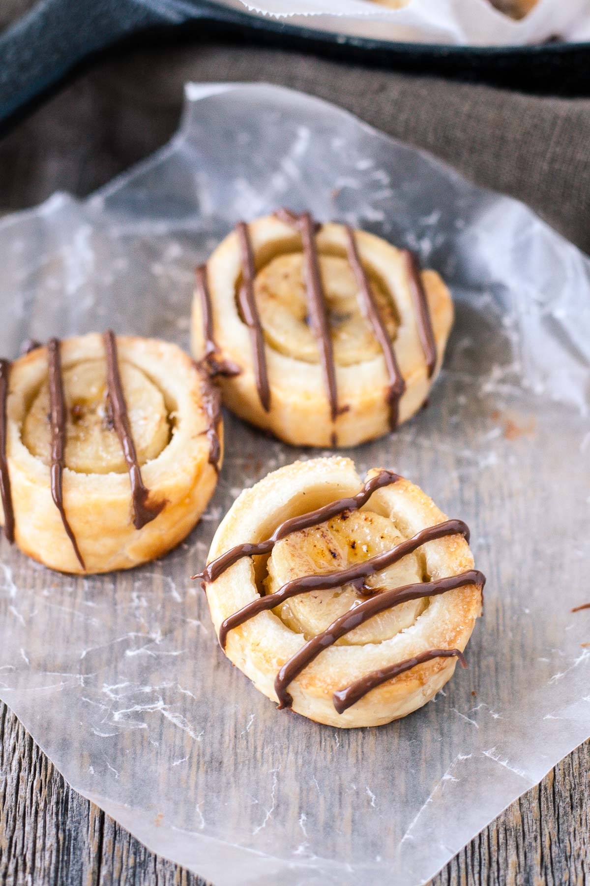 Banana bites drizzled with chocolate on a piece of parchment.