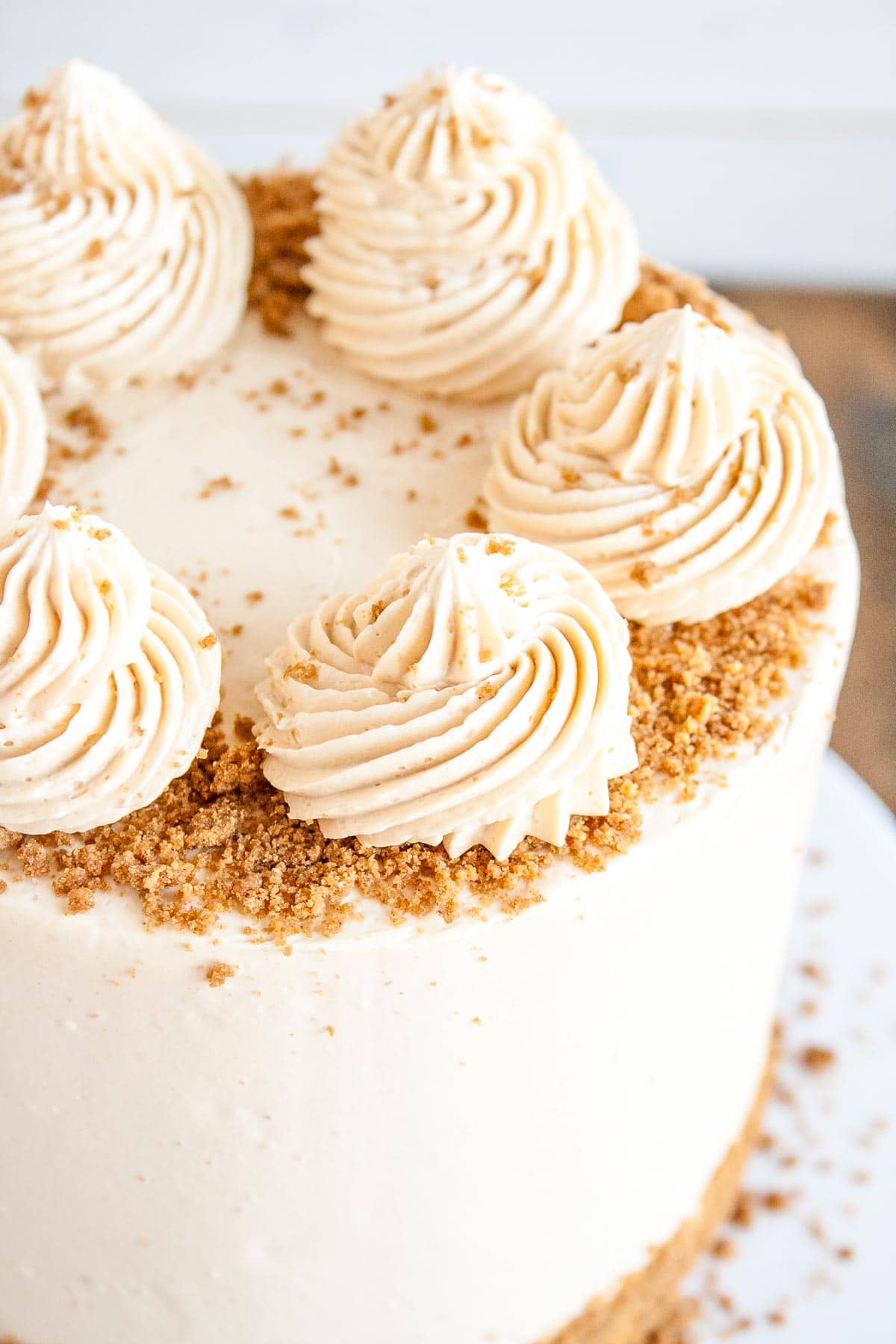 This Biscoff Cake pairs fluffy vanilla cake layers with a sweet cookie butter frosting and crushed speculoos cookies. | livforcake.com Close up of a rosette on top of the cake.