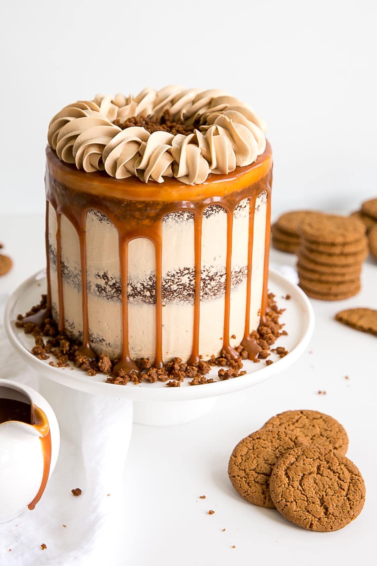 The classic Gingerbread Cake gets a delicious makeover! Gingerbread cake layers and caramel buttercream paired with gingersnap streusel and homemade caramel. | livforcake.com Caramel Gingerbread Cake decorated naked cake style with a caramel drip and rope border on top.