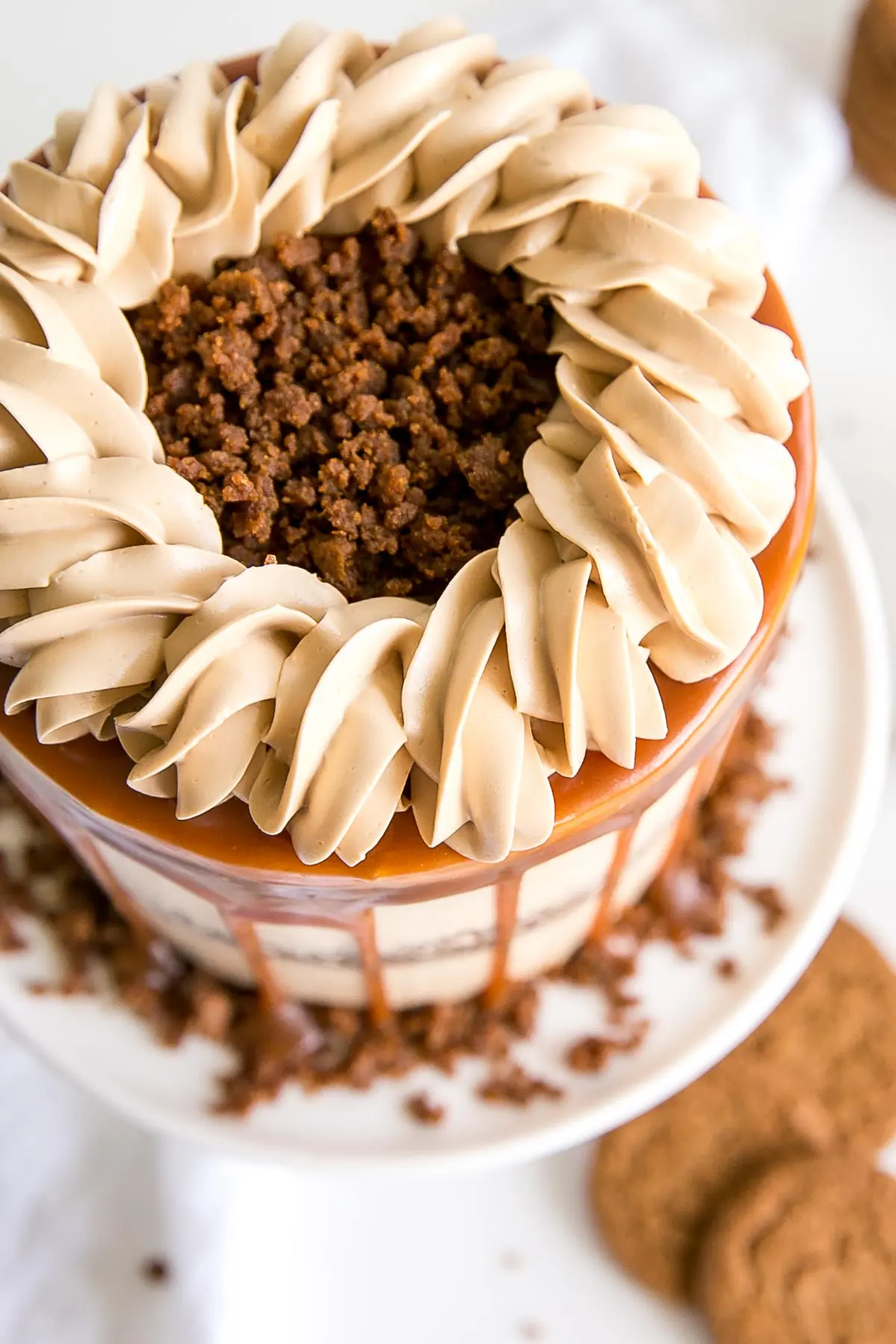 The classic Gingerbread Cake gets a delicious makeover! Gingerbread cake layers and caramel buttercream paired with gingersnap streusel and homemade caramel. | livforcake.com Top view showing caramel buttercream rope border and gingersnap streusel.