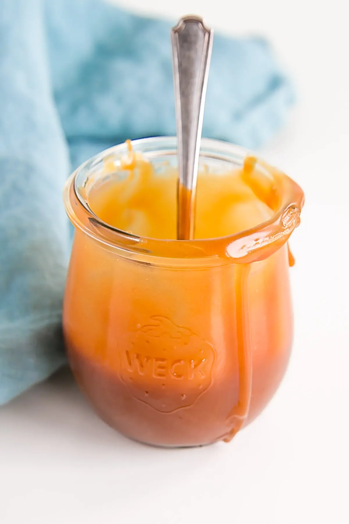 Half empty jar of caramel with a spoon inside it.