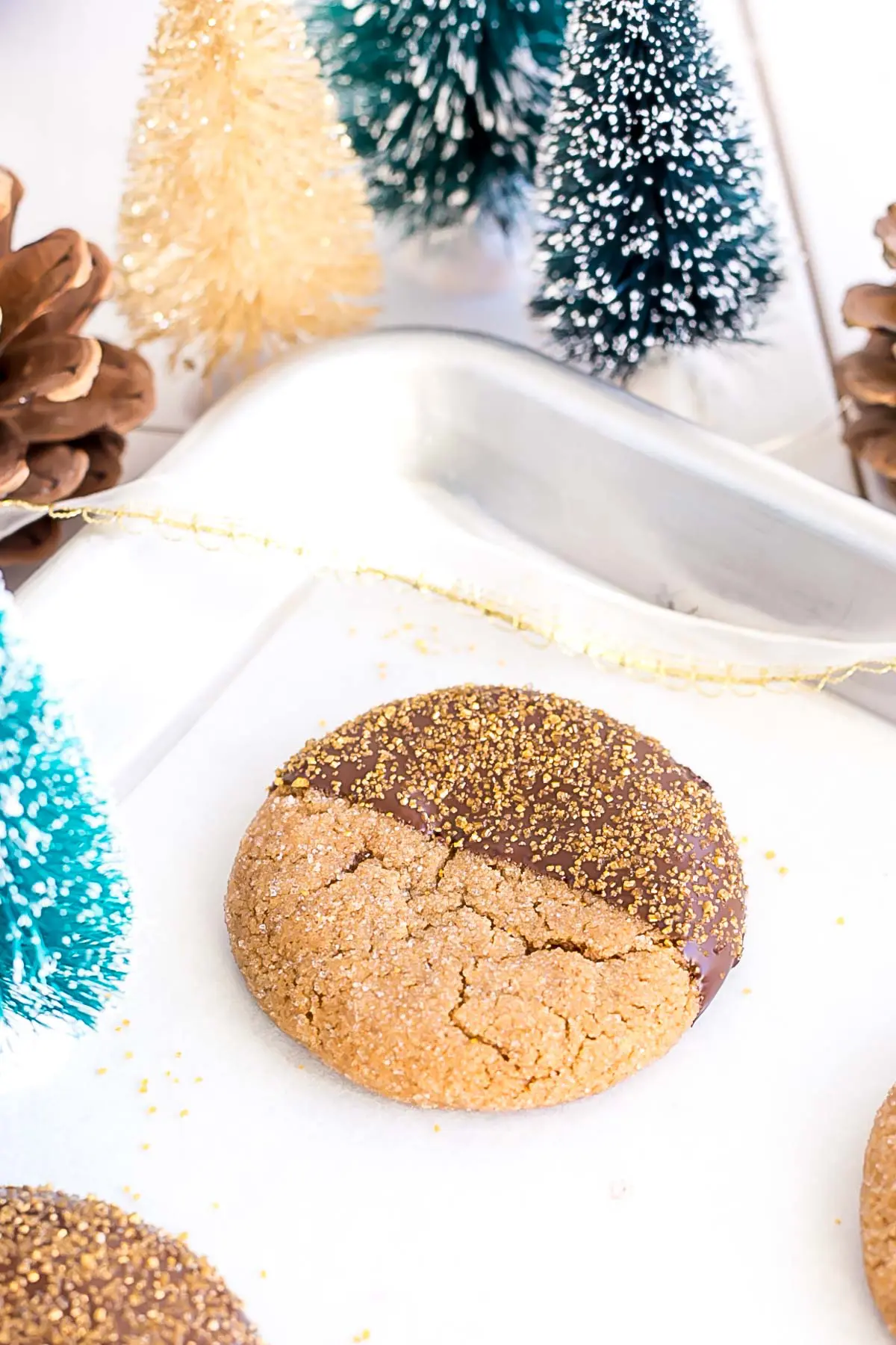 These Chocolate Dipped Gingerbread Cookies are the perfect treat for the holiday season! Chewy ginger spiced cookies dipped in dark chocolate. | livforcake.com Chocolate dipped cookie on a baking sheet.