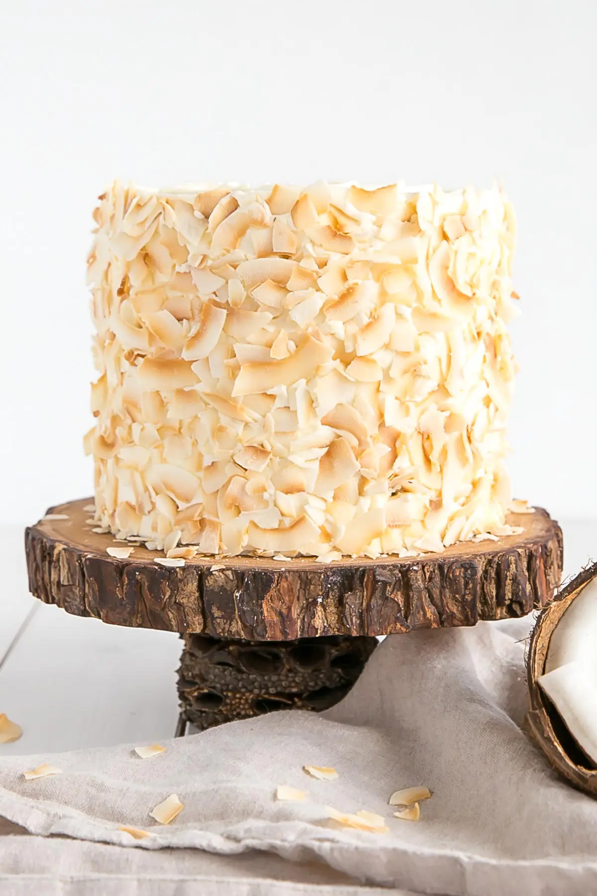 This moist and delicious coconut cake recipe is infused with natural coconut flavour throughout and decorated with giant toasted coconut flakes. | livforcake.com Coconut cake with toasted coconut flakes.