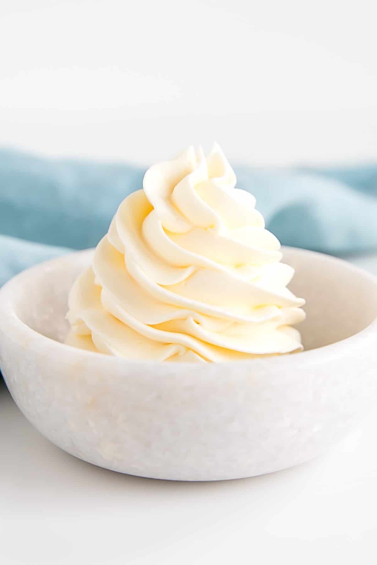 This custard-based German buttercream is made with just a few simple ingredients. Perfect for those who like a rich and silky frosting that isn't too sweet! | livforcake.com Rosette of German buttercream in a small bowl.