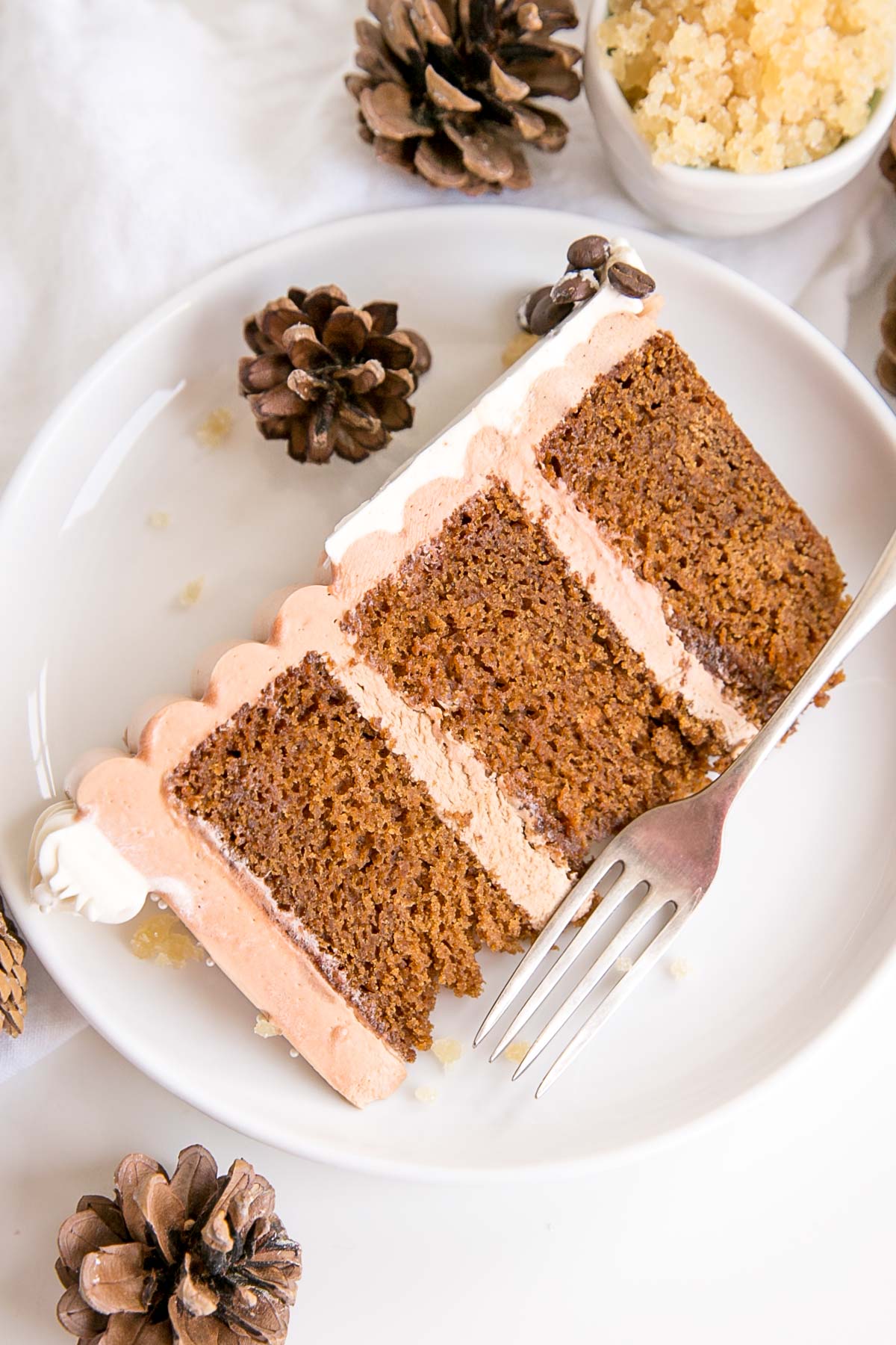 This Gingerbread Latte Cake is your favourite Holiday drink in cake form! Gingerbread spice cake layers with an espresso buttercream. | livforcake.com Slice of gingerbread latte cake on a plate.