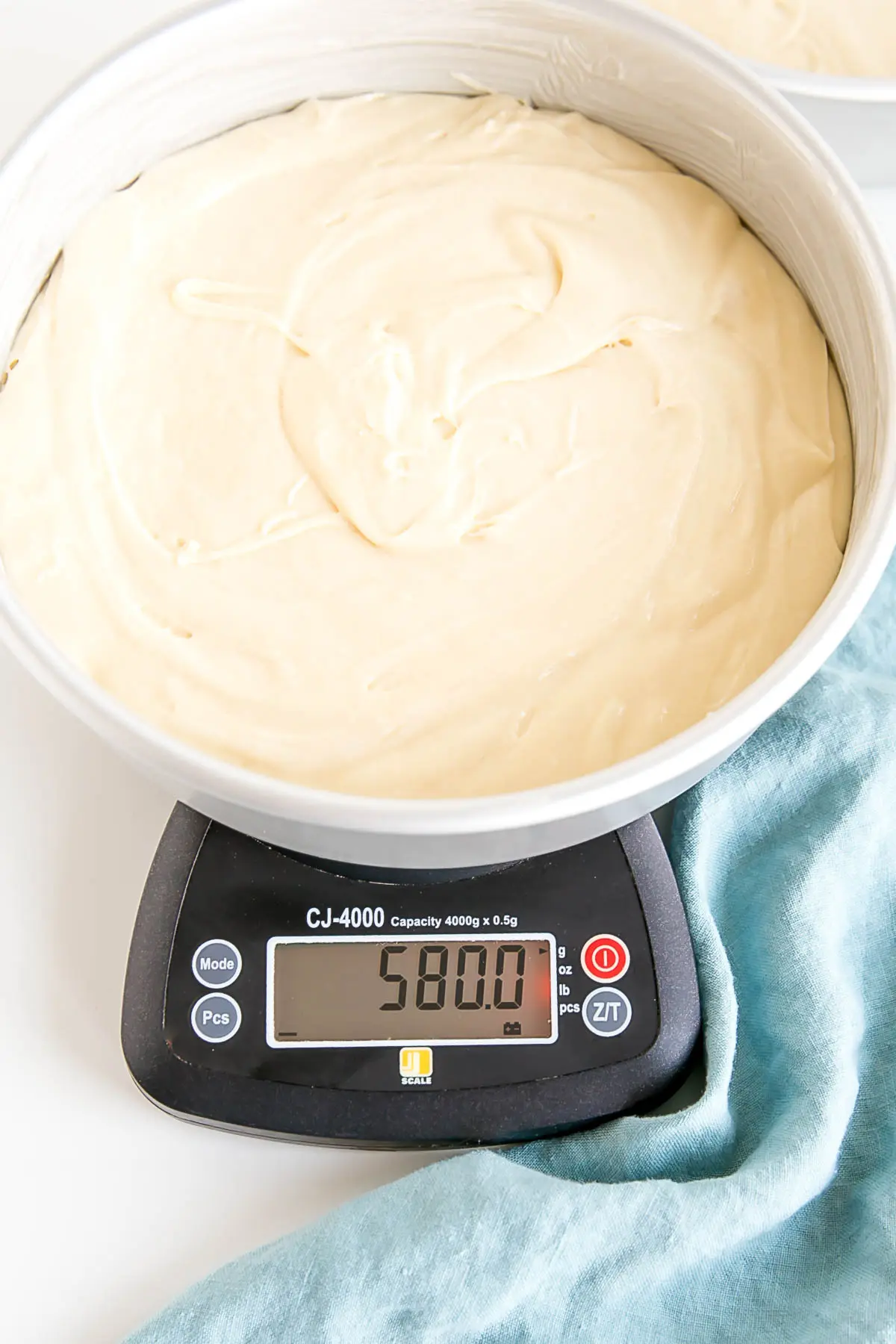 Learn how to bake flat cakes every single time! A simple tutorial on how to make sure your cakes come out nice and flat straight out of the oven. | livforcake.com Cake pan filled with cake batter on a kitchen scale.