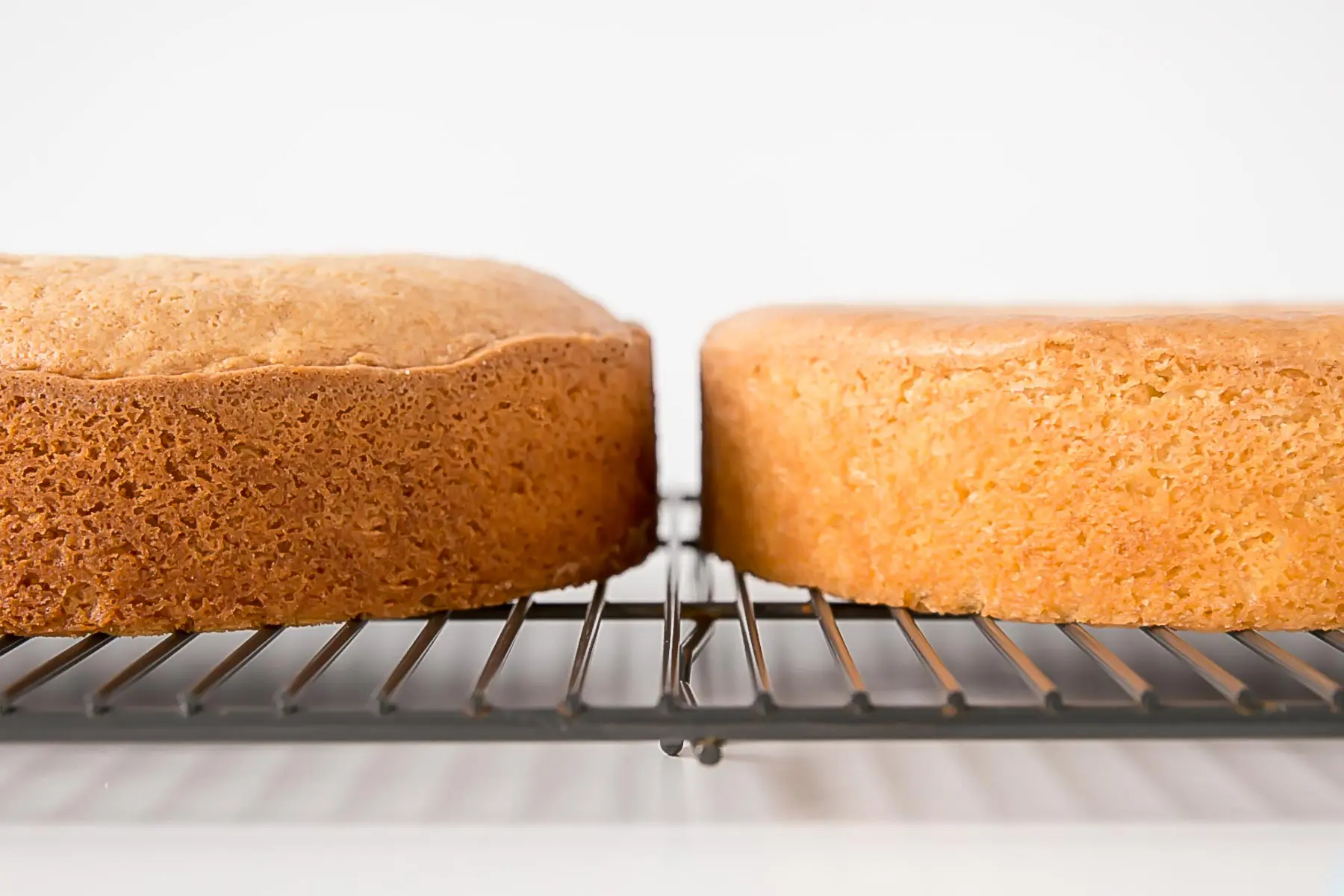 Learn how to bake flat cakes every single time! A simple tutorial on how to make sure your cakes come out nice and flat straight out of the oven. | livforcake.com Close up of the two cakes beside each other.