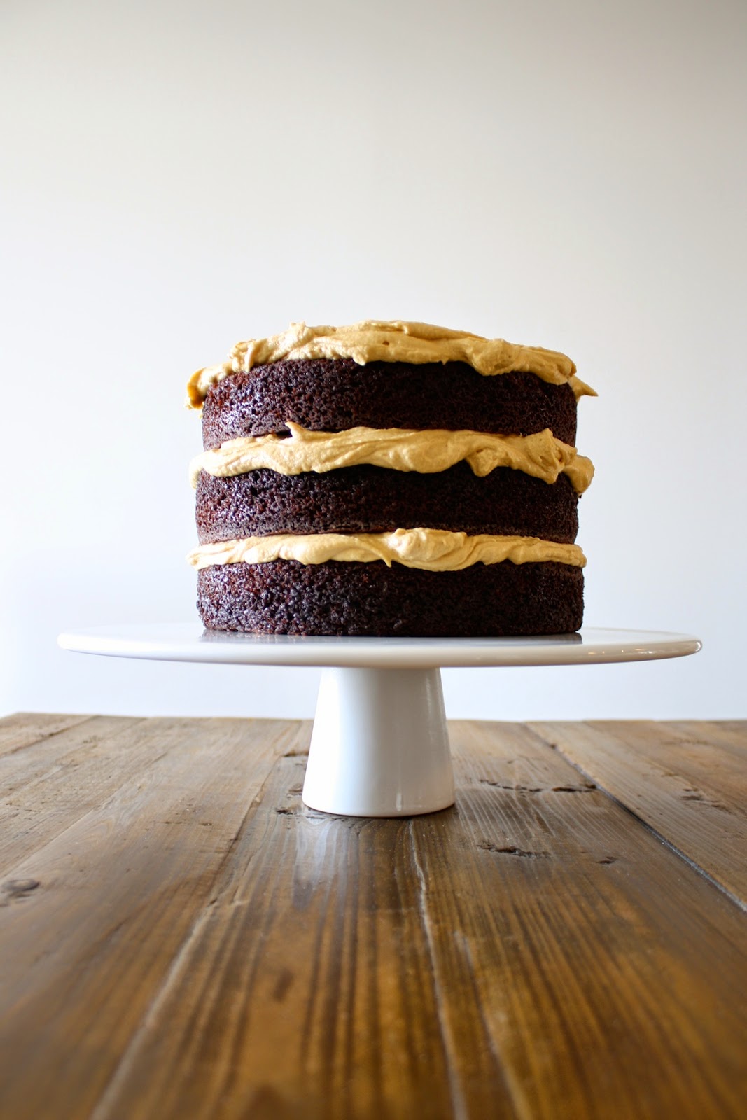 A cake on a white cake stand sitting on top of a wooden table