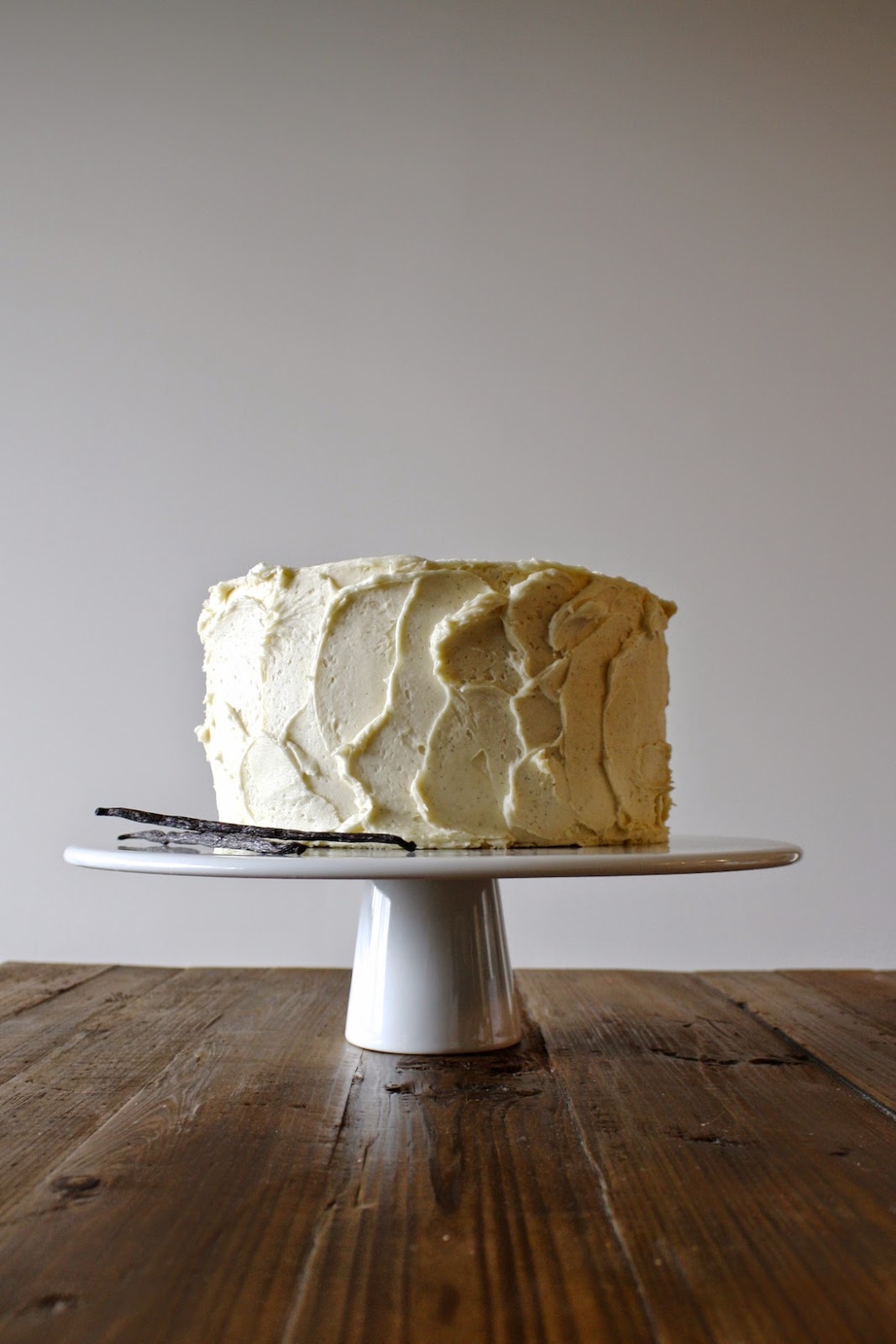 A cake on a white cake stand sitting on top of a wooden table