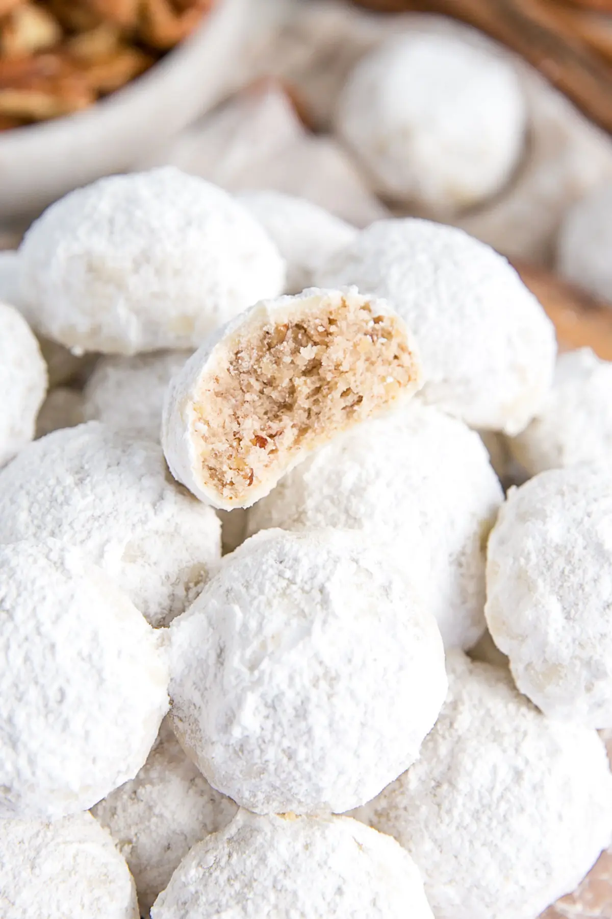 These Mexican Wedding Cookies (also known as Snowball Cookies or Russian Tea Cakes) are buttery, melt-in-your-mouth delicious! Pecan cookies with a hint of cinnamon dusted with powdered sugar. | livforcake.com Close up of a cookie with a bite taken out.