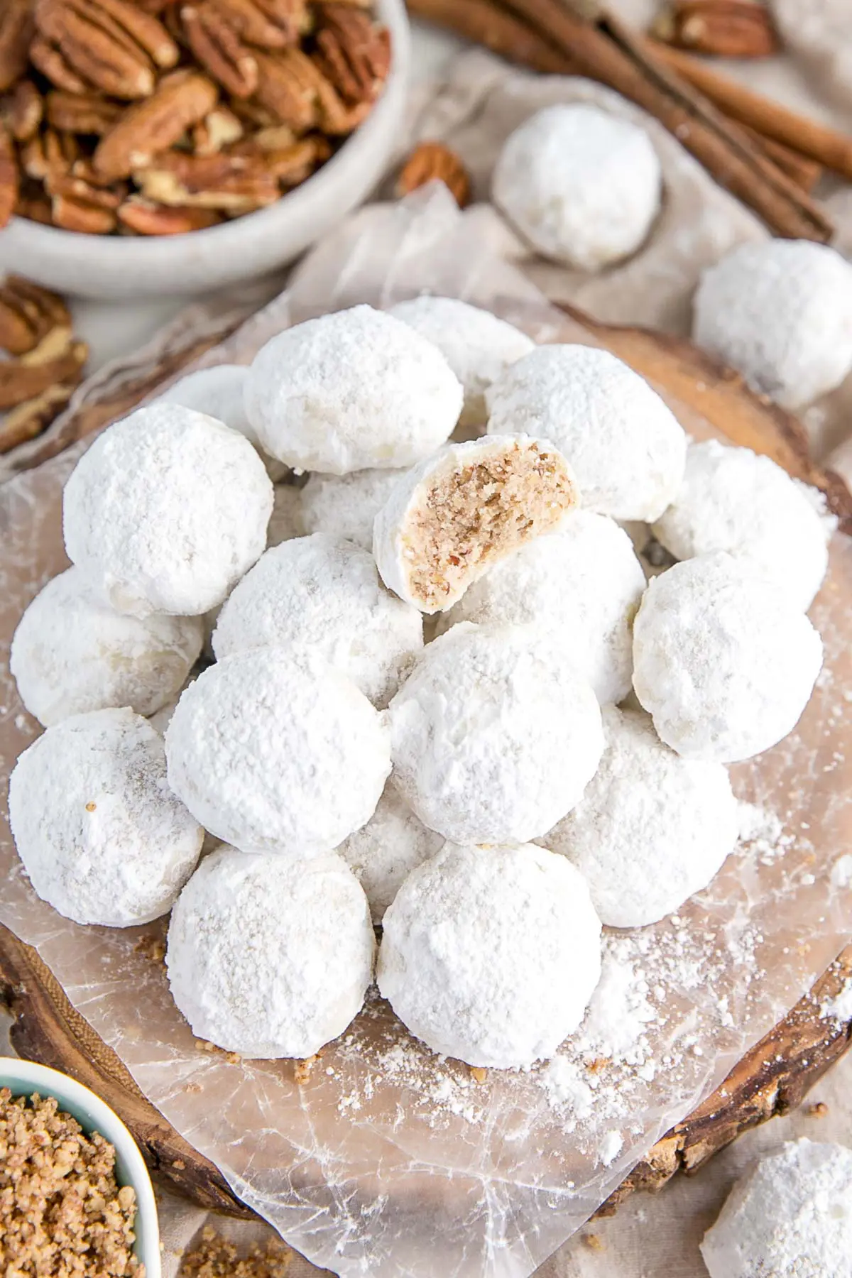 These Mexican Wedding Cookies (also known as Snowball Cookies or Russian Tea Cakes) are buttery, melt-in-your-mouth delicious! Pecan cookies with a hint of cinnamon dusted with powdered sugar. | livforcake.com Stack of snowball cookies on a plate.