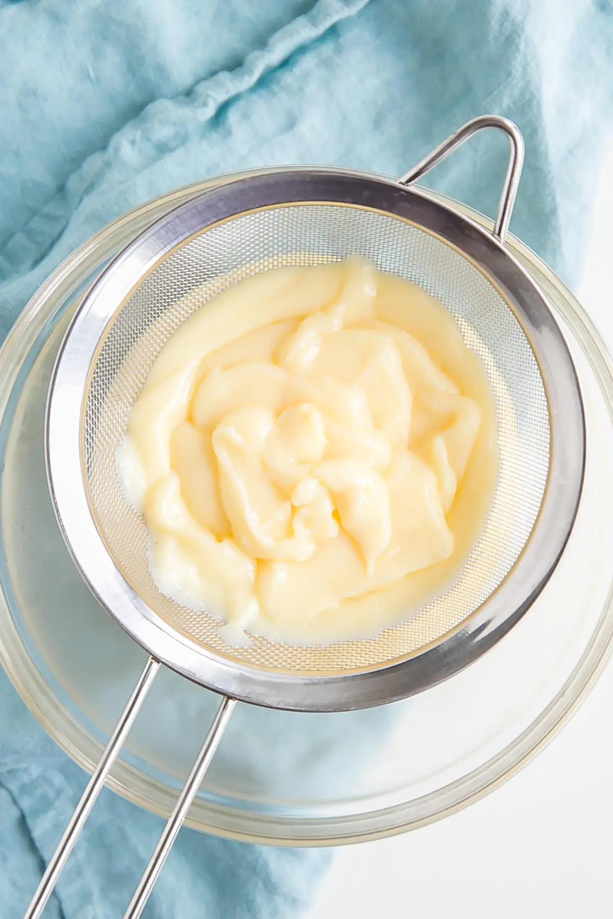 This easy Pastry Cream (Creme Patissiere) recipe is simple and delicious. A rich and creamy vanilla custard you can use in a variety of decadent desserts. | livforcake.com Passing the custard through a strainer.
