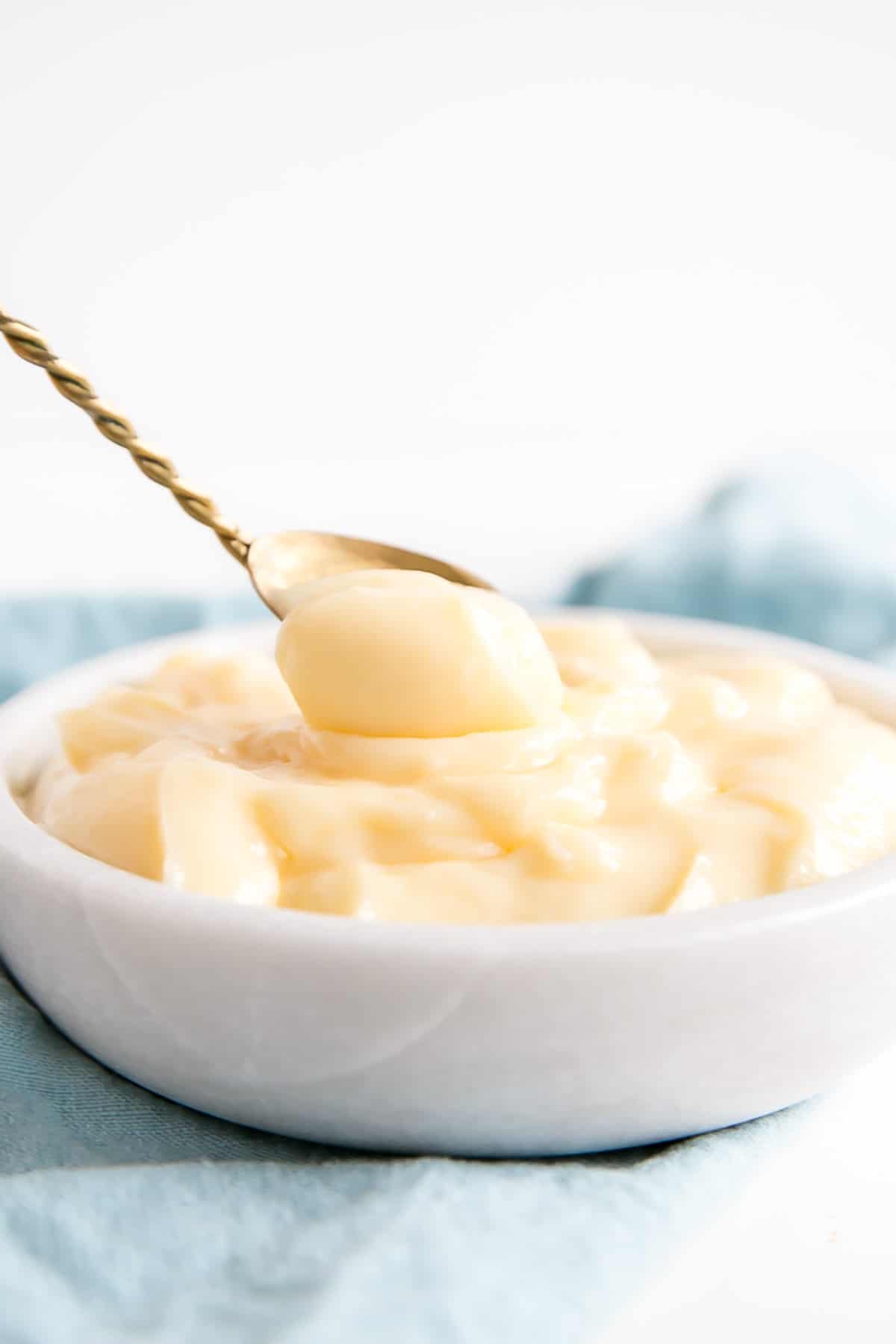 This easy Pastry Cream (Creme Patissiere) recipe is simple and delicious. A rich and creamy vanilla custard you can use in a variety of decadent desserts. | livforcake.com A spoon dipping into the bowl of pastry cream.