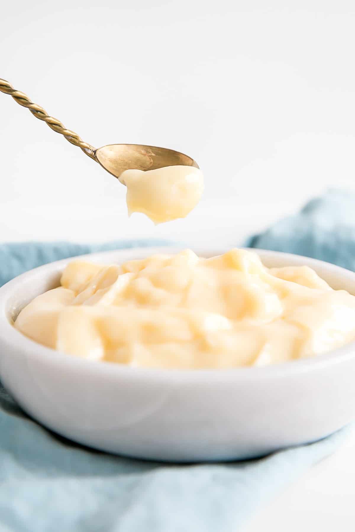 This easy Pastry Cream (Creme Patissiere) recipe is simple and delicious. A rich and creamy vanilla custard you can use in a variety of decadent desserts. | livforcake.com Vanilla custard on a spoon.