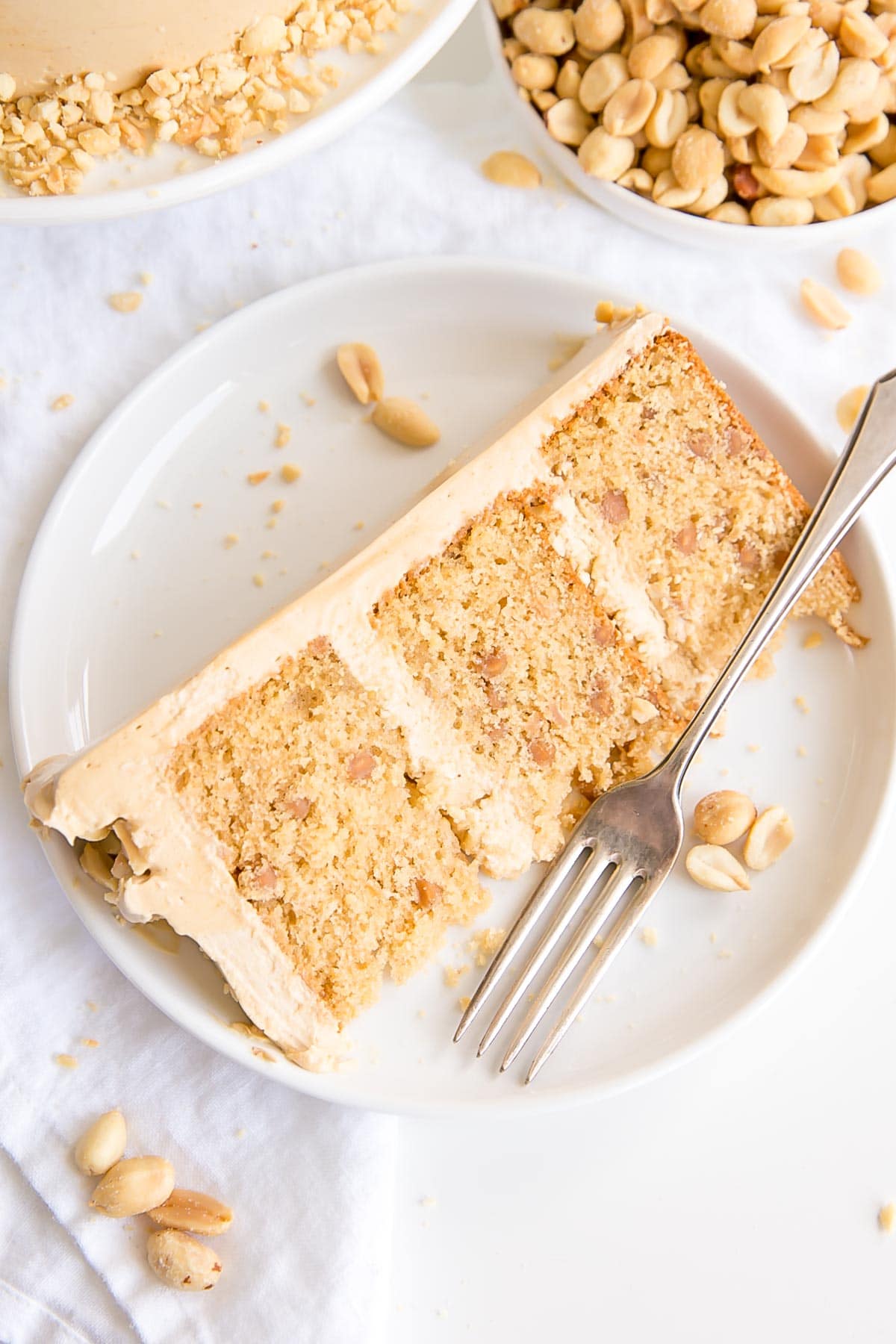 Peanut butter lovers, this cake is for you! Peanut butter cake layers studded with peanut butter chips covered in a peanut butter Swiss meringue buttercream. | livforcake.com Slice of cake on a plate.