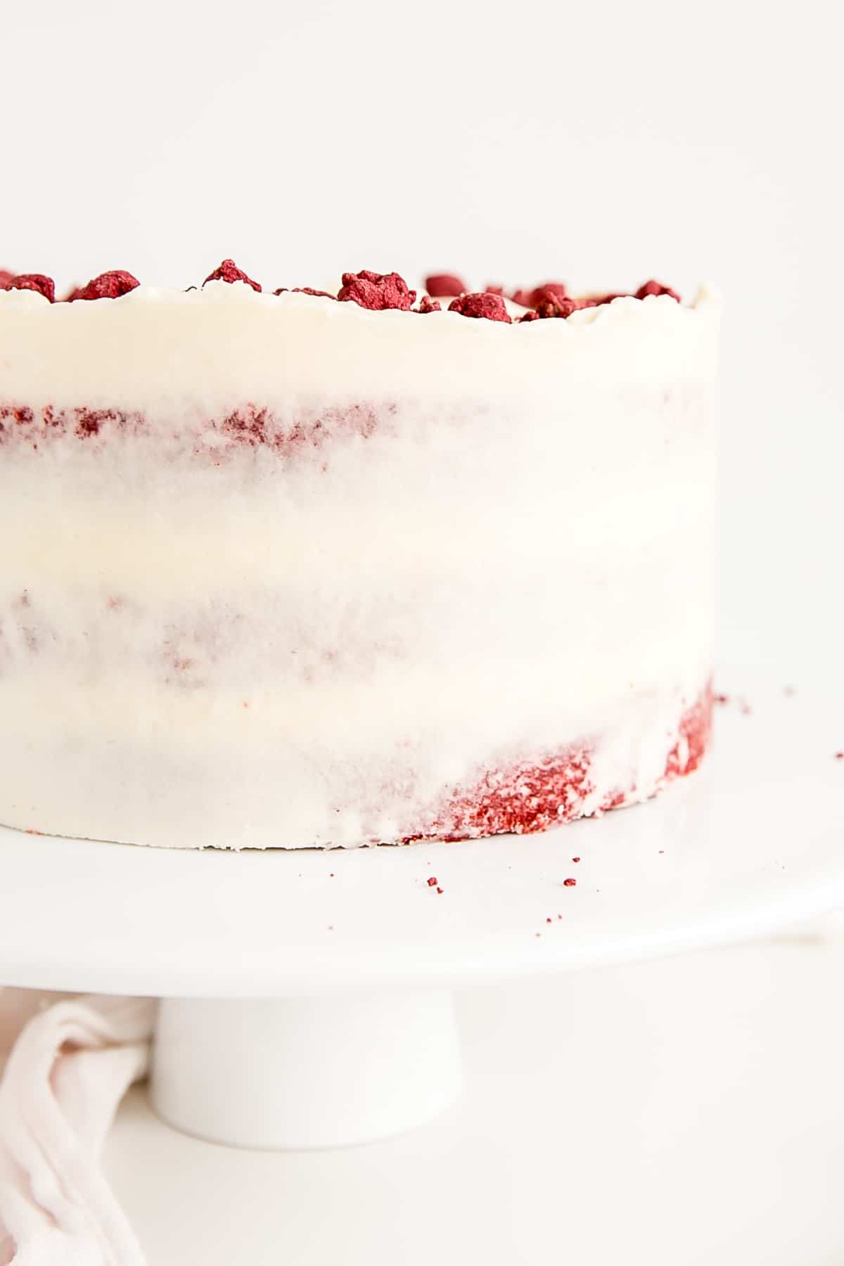 Classic Red Velvet Cake! Tender red cake layers with a hint of chocolate paired with a tangy cream cheese frosting and a red velvet crumble. | livforcake.com Close up of side of the cake.