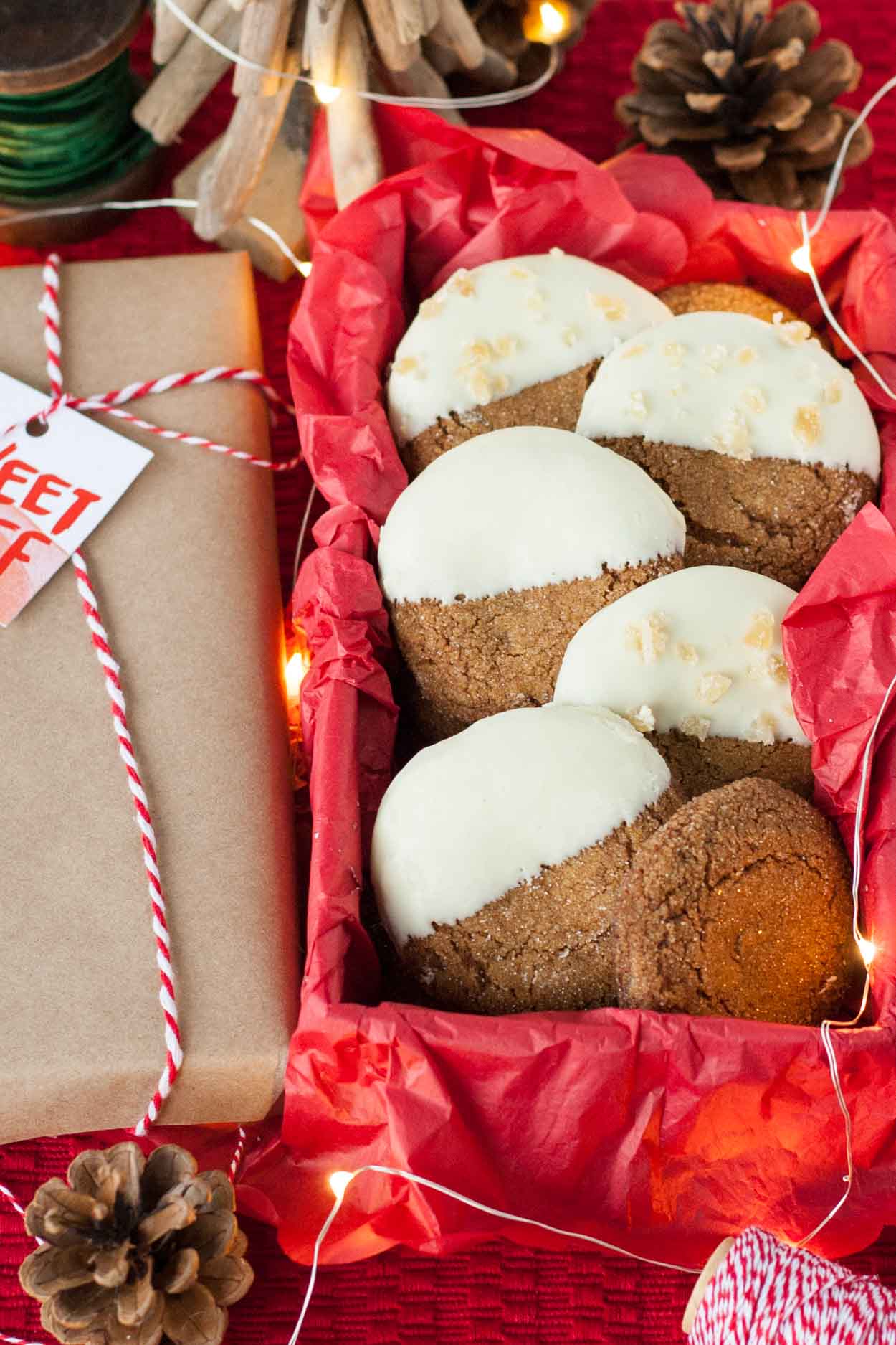 These Snow Capped Gingersnaps are the perfect Christmas cookies! Chewy gingerbread cookies dipped in white chocolate and topped with crystallized ginger. | livforcake.com A box of white chocolate dipped chewy gingerbread cookies