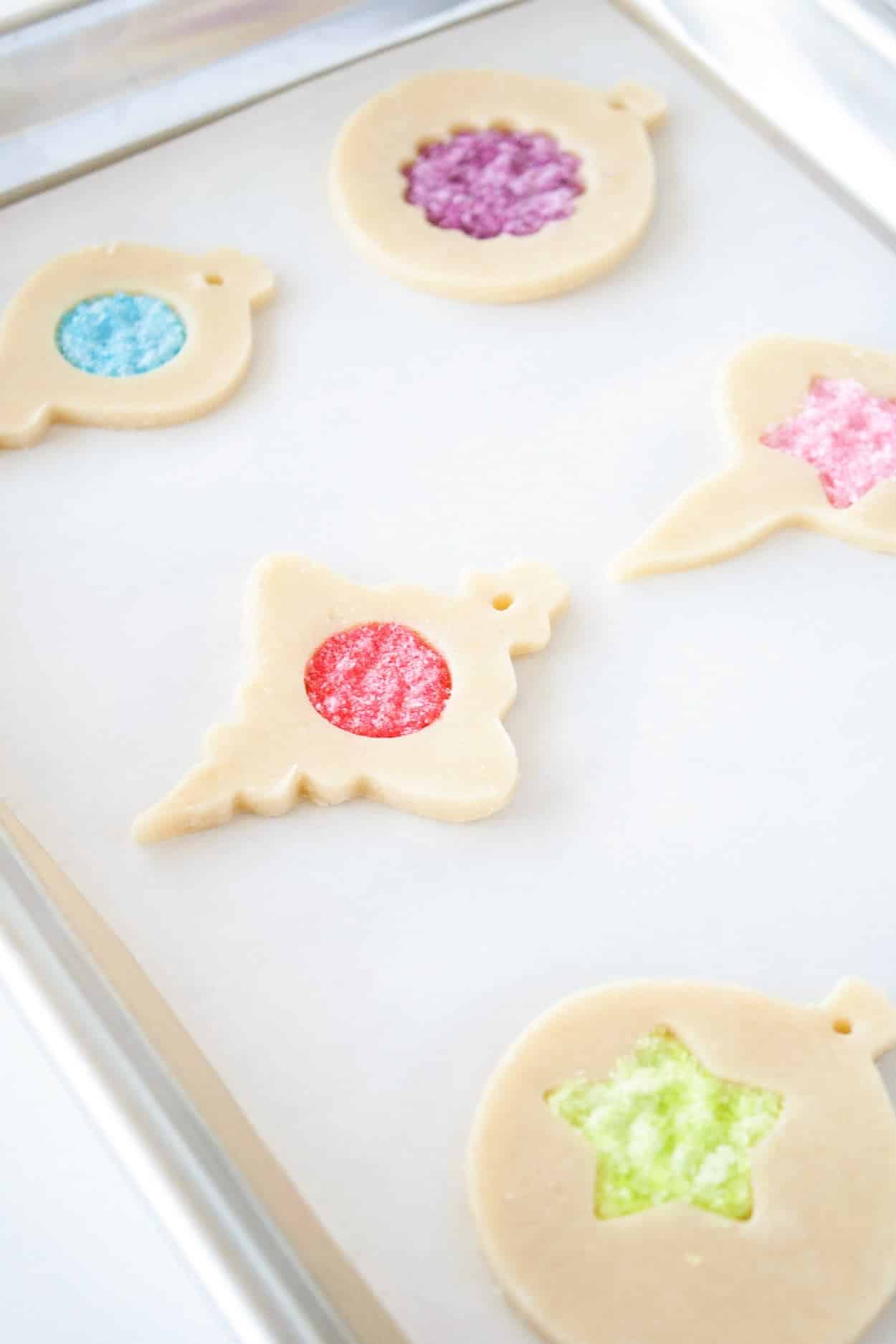 Learn how to make stunning stained glass cookies with this detailed tutorial! Perfect for holiday cookie exchanges or hanging on your tree. | livforcake.com Unbaked stained glass cookies on a cookie sheet