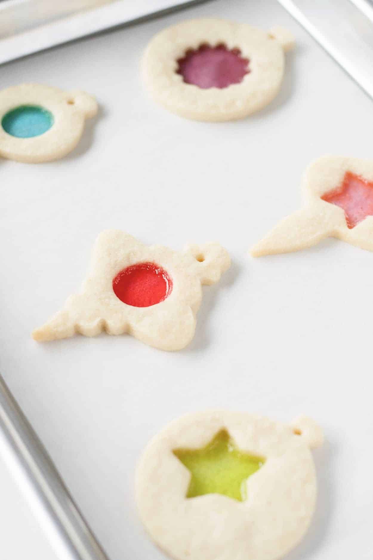 Learn how to make stunning stained glass cookies with this detailed tutorial! Perfect for holiday cookie exchanges or hanging on your tree. | livforcake.com Baked stained glass cookies on a baking sheet.