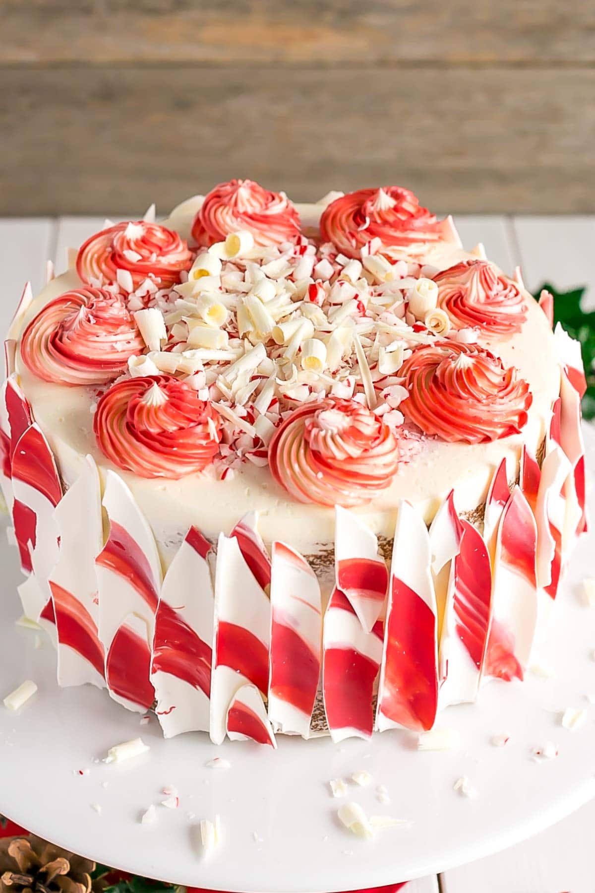 This White Chocolate Candy Cane Cake is the perfect addition to your holiday celebrations! | livforcake.com Angled shot showing two toned rosettes on the top of the cake.